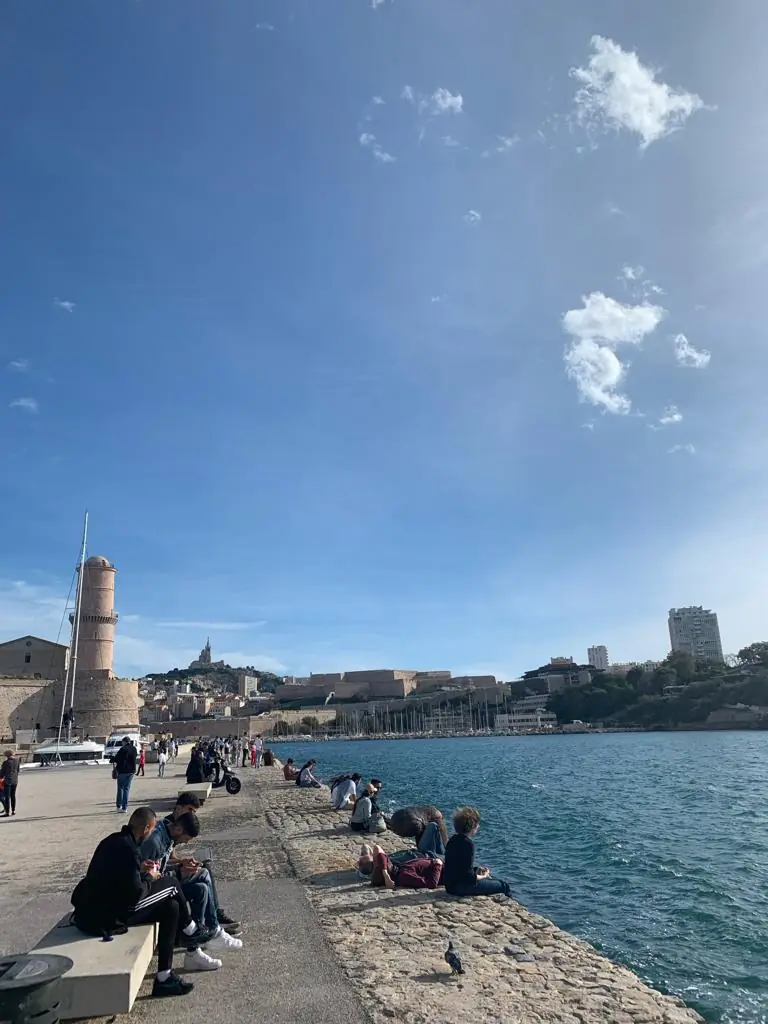Die Einfahrt des Vieux-Port mit dem Fort Saint-Jean, Menschen sitzen auf dem Kai